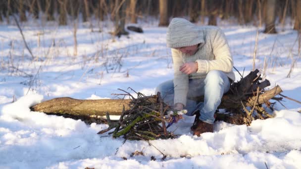 Un hombre enciende un encendedor en el bosque de invierno — Vídeo de stock