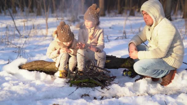 Dad, daughters sitting campfire in winter forest — ストック動画