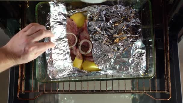 Close oven in which foil baked pork neck, potatoes — Stock videók