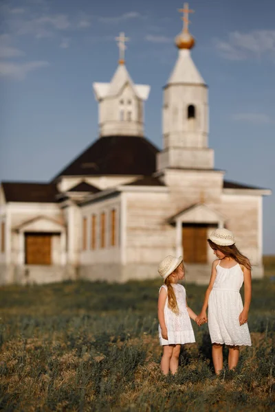 Mädchen halten Händchen und stellen sich gegen Holzkirche — Stockfoto