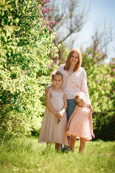 Moeder met dochters staan tussen de lila struiken — Stockfoto