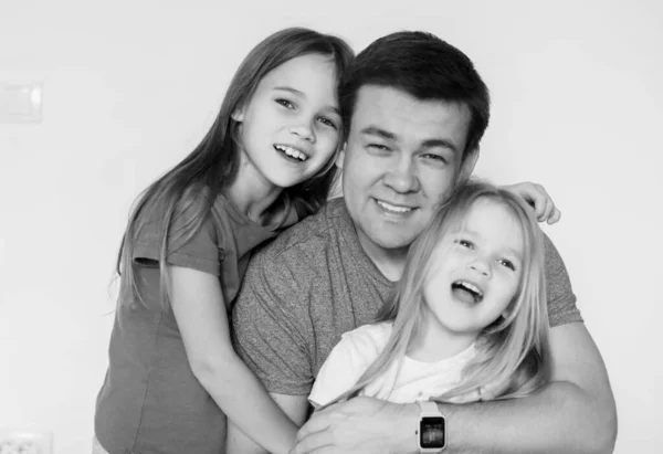 daddy and two daughters hug each. black-white.