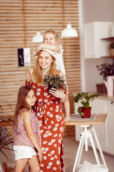 Mamá e hijas con flores de interior en la cocina — Foto de Stock