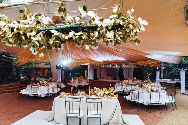 Wedding decor. tables in outdoor tent evening.