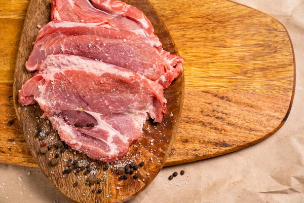 Schweinefleisch auf Holzbrett mit Salz, Pfeffer und freiem Platz — Stockfoto