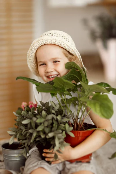 Little girl with indoor flowers into pot Royalty Free Stock Images