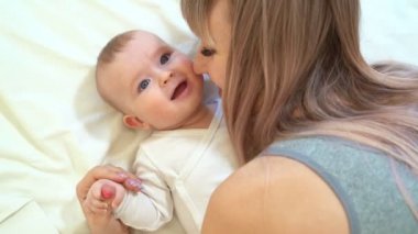 a mom and son lying on bed. baby learns to crawl.
