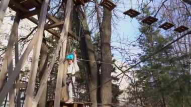 small girl is afraid, learns to climb rope Park.