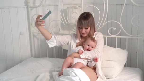 Мама с детской кроватью делает селфи на смартфоне — стоковое видео