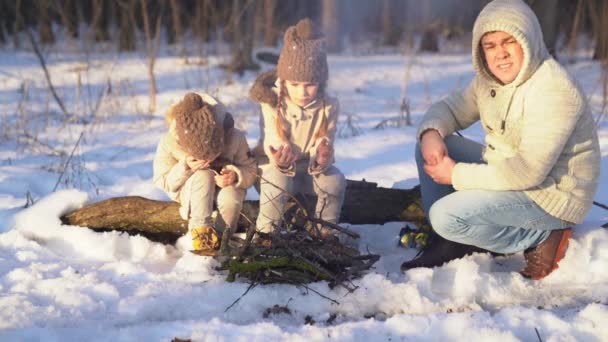 Dad, daughters sitting campfire in winter forest — Stockvideo