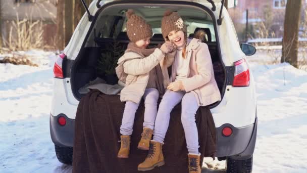 Hermanas sentadas en el maletero del coche y tirar de la cola — Vídeos de Stock