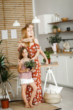 Anne ve kızları mutfaktaki çiçeklerle
