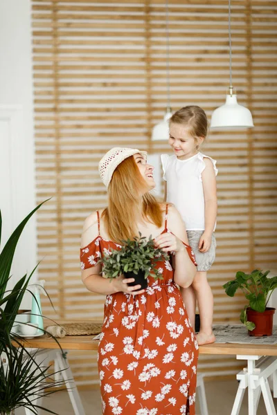 Moeder en dochter met indoor bloemen in de keuken — Stockfoto