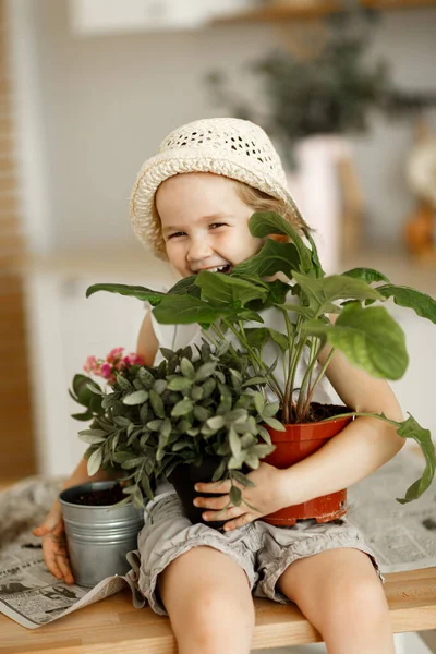 little girl with indoor flowers into pot