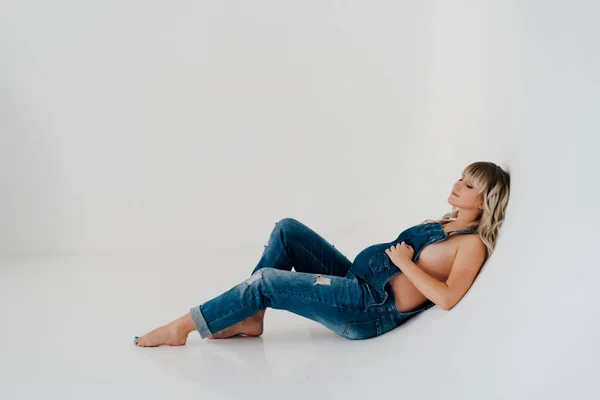 Gravid lögn i denim overall på vit bakgrund — Stockfoto