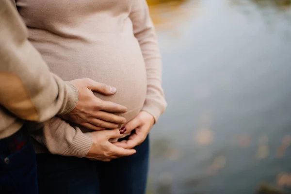 Coppia che si tiene per mano sulla pancia di una ragazza incinta — Foto Stock