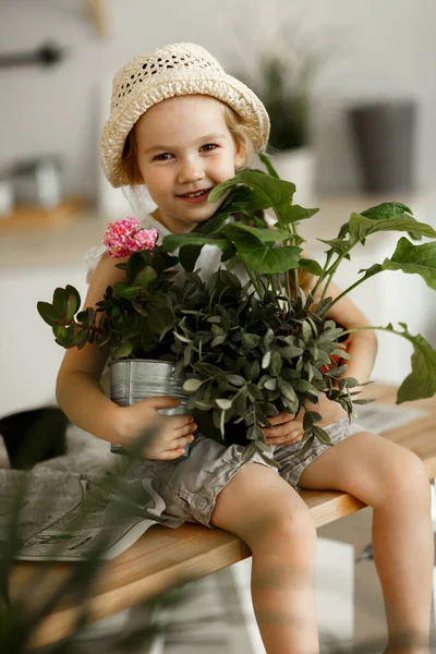 Klein meisje met indoor bloemen in pot — Stockfoto