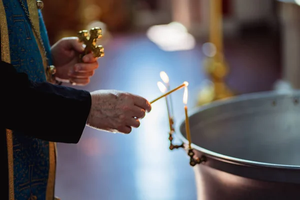 Priester steekt kaars aan bij doopvont — Stockfoto