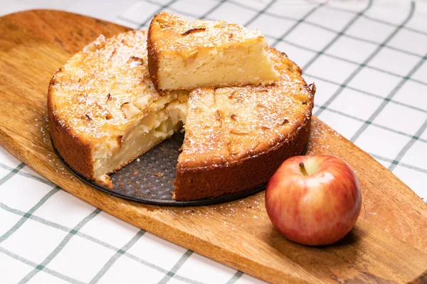 Отрезать часть домашнего торта и красное яблоко на деревянной доске . — стоковое фото