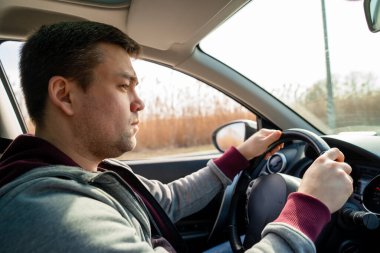 Arabanın direksiyonundaki gri kazaklı üzgün adam. sazlıklar