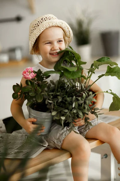 little girl with indoor flowers into pot