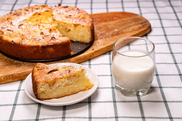 Tagliare parte torta fatta in casa e latte di vetro di legno — Foto Stock
