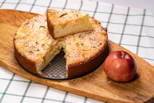 Teil hausgemachten Kuchen und einen roten Apfel auf Holzbrett abschneiden. — Stockfoto