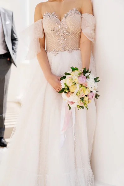 Руки невесты с букетом на фоне платья — стоковое фото