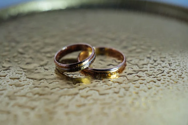 Dos anillos de boda en la superficie del espejo gotas de agua — Foto de Stock