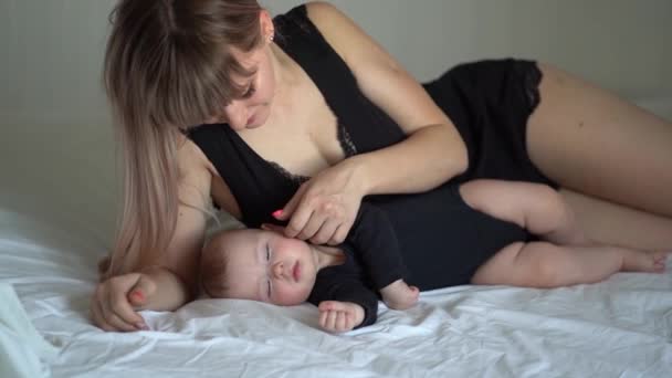 Мать и ребенок в черном спят вместе на кровати — стоковое видео