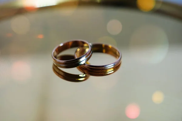 Dos anillos de boda en espejo brillante como superficie . — Foto de Stock