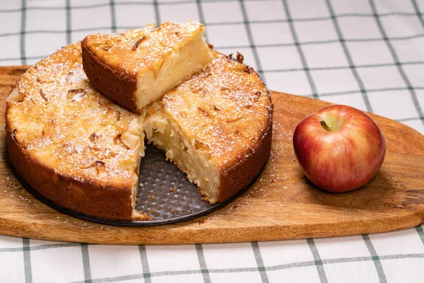Teil hausgemachten Kuchen und einen roten Apfel auf Holzbrett abschneiden. — Stockfoto