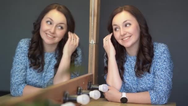 Brunette meisje in blauwe jurk op zoek in spiegel — Stockvideo