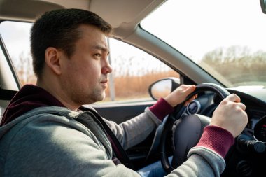 Araba sazlıklarının arkasındaki gri kazaklı üzgün adam.