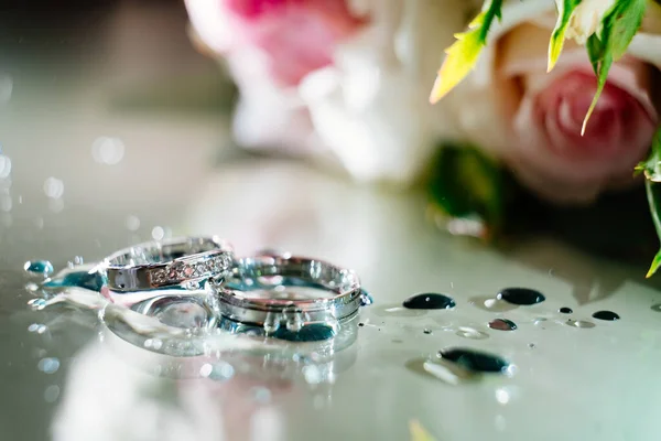 Rings with drops of water on background of bouquet — Stock Photo, Image
