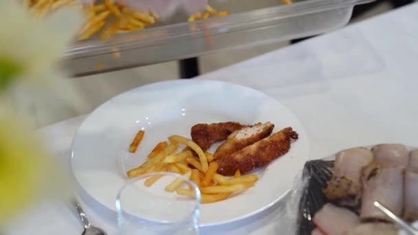 Ένας σερβιτόρος που φοράει γάντια βάζει ένα πιάτο πατάτες. — Αρχείο Βίντεο