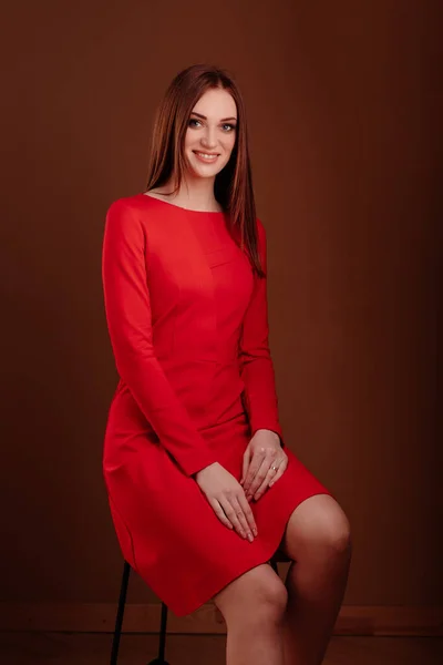 Menina bonita em vestido vermelho sentado em uma cadeira — Fotografia de Stock