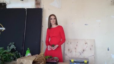 Kırmızı elbiseli kız yenilenmiş bir odada duruyor.