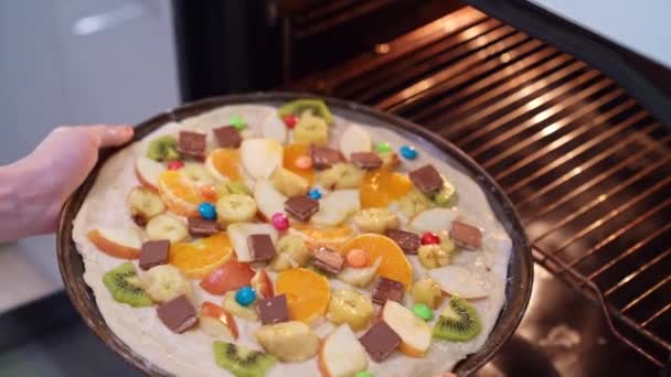 Gyerekek kéz tesz a sütőbe egy édes pizza — Stock videók