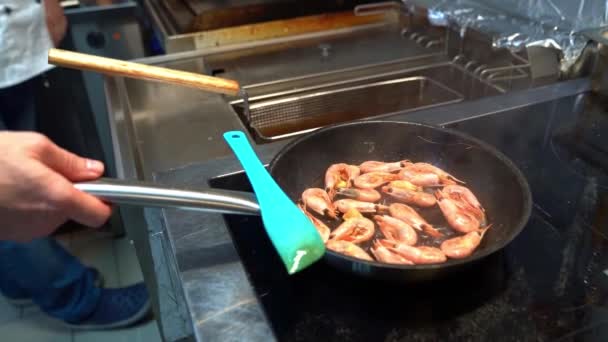 Kock justerar pan med räkor på spisen. — Stockvideo