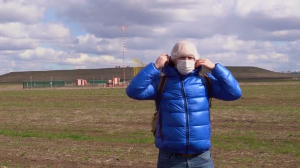 Egy férfi orvosi maszkban, kék kabátban, csuklyában. — Stock videók