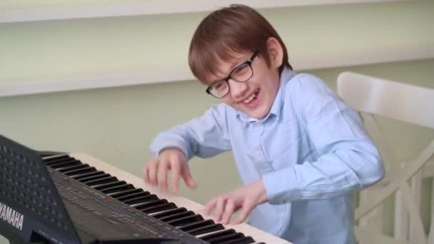 Grappig jongen in bril speelt de synthesizer. — Stockvideo