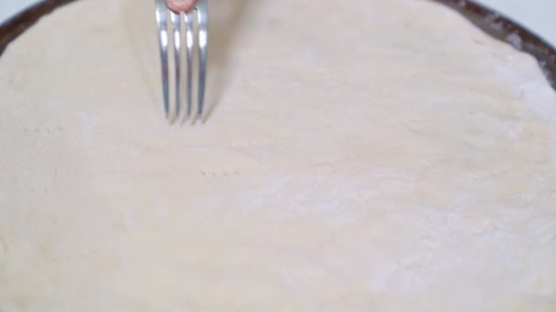 Hand with a fork, pierce pizza dough in pan — Stock Video