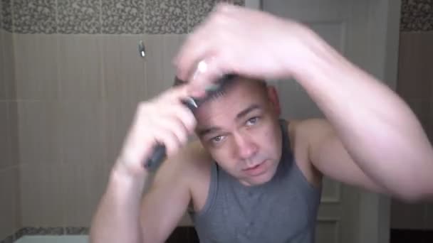 未刮胡子的男人早上在浴室里梳头 — 图库视频影像