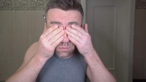 Un hombre somnoliento y sin afeitar se frota los ojos con las manos — Vídeo de stock