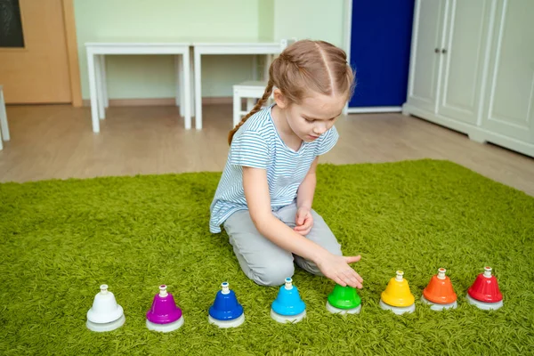 Niña jugando con coloridas campanas musicales . — Foto de Stock