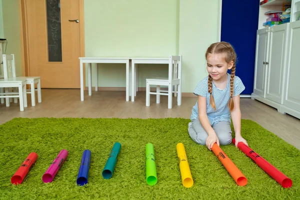Niña jugando con tubos musicales de colores . — Foto de Stock