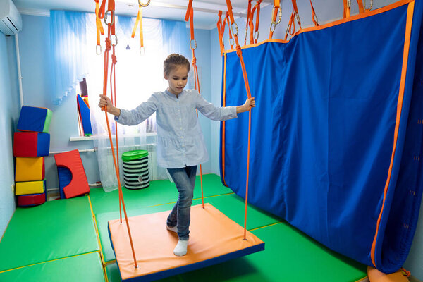 маленькая девочка на платформе сенсорной интеграции
 