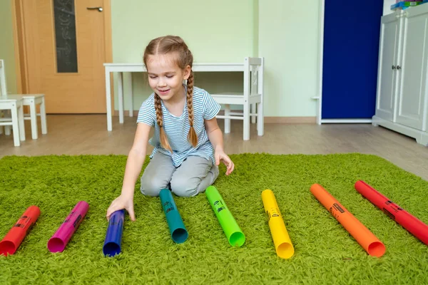 Chica jugando con coloridos tubos musicales . — Foto de Stock