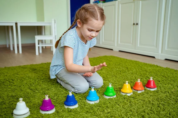 Chica jugando con coloridas campanas musicales . — Foto de Stock
